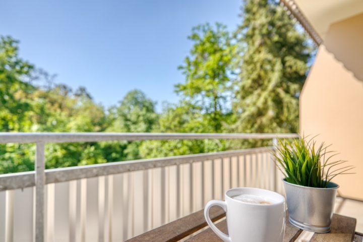 Kaffeetasse auf einem Balkontisch mit Blick auf die Bäume