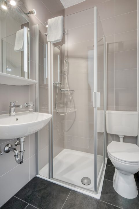 Badezimmer mit gläserner Duschkabine und Waschtisch