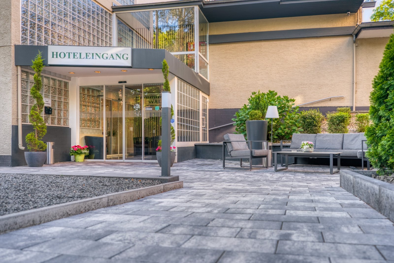 Hoteleingang mit gepflastertem Vorplatz und Sitzgelegenheiten