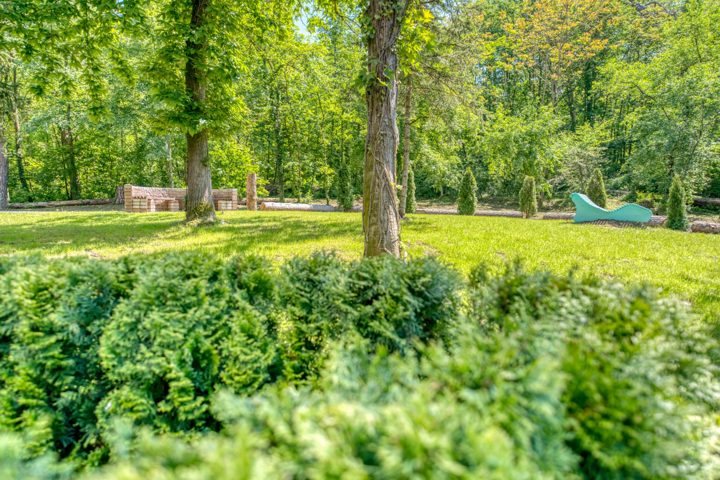Grüner Hotelgarten mit hohen Bäumen und Rasenflächen