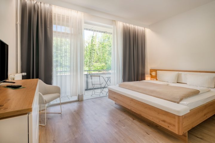 Schlafbereich der Suite mit Holzbett, Schreibtisch und Balkon