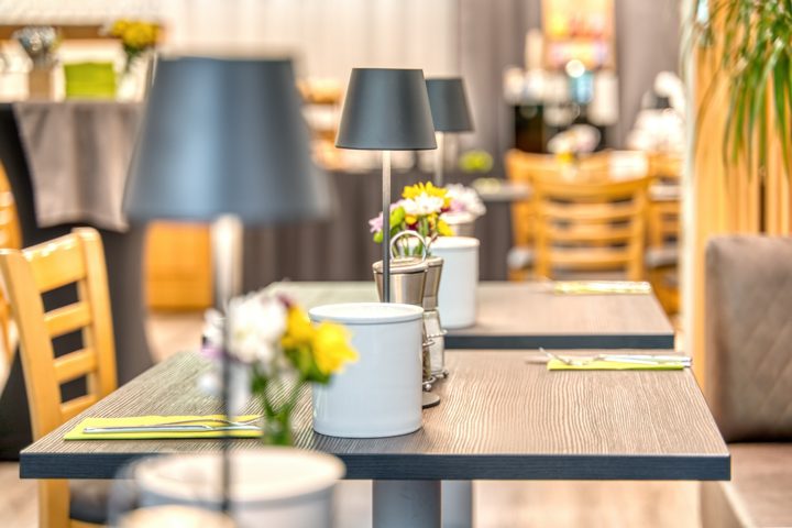 Gedeckte Frühstückstische mit Blumen und kleinen Tischleuchten